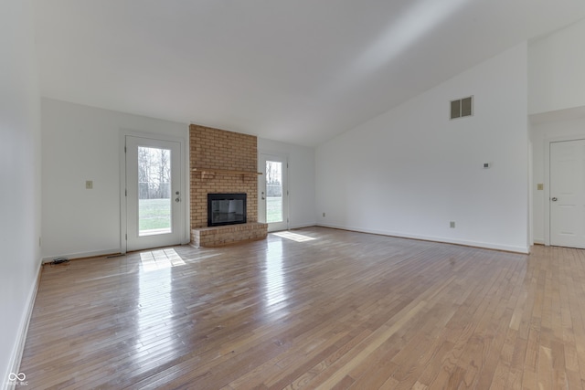 unfurnished living room featuring visible vents, baseboards, a brick fireplace, and light wood finished floors