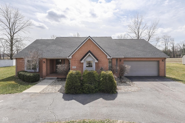 view of front of property featuring brick siding, an attached garage, a shingled roof, a front yard, and driveway