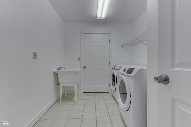 washroom featuring washing machine and clothes dryer, laundry area, baseboards, and light tile patterned floors