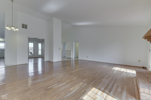 unfurnished living room with baseboards, visible vents, high vaulted ceiling, and light wood-style floors