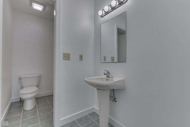 half bath featuring tile patterned floors, toilet, and baseboards