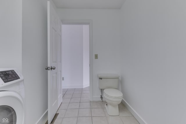 bathroom with tile patterned flooring, washer / dryer, toilet, and baseboards