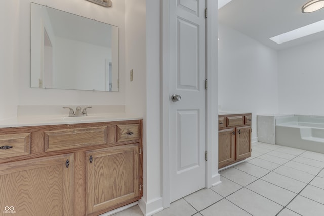 full bath featuring tile patterned floors, a skylight, vanity, and a garden tub