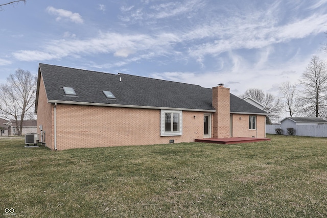 rear view of house with a yard, central AC, a chimney, a deck, and brick siding