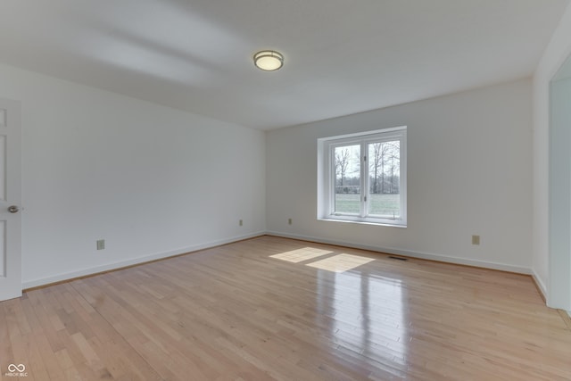 spare room with visible vents, light wood-style flooring, and baseboards