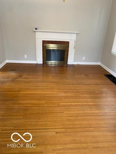 unfurnished living room with hardwood / wood-style flooring and a tiled fireplace