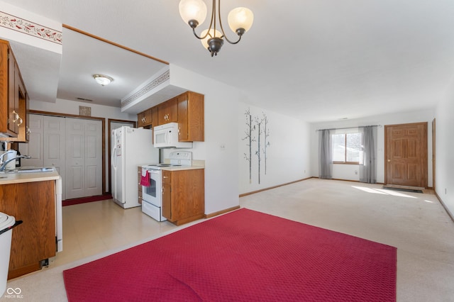 kitchen featuring light carpet, decorative light fixtures, sink, and white appliances