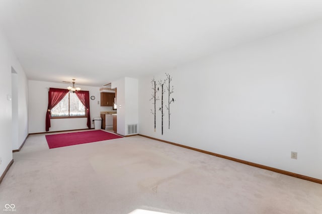 carpeted empty room featuring an inviting chandelier