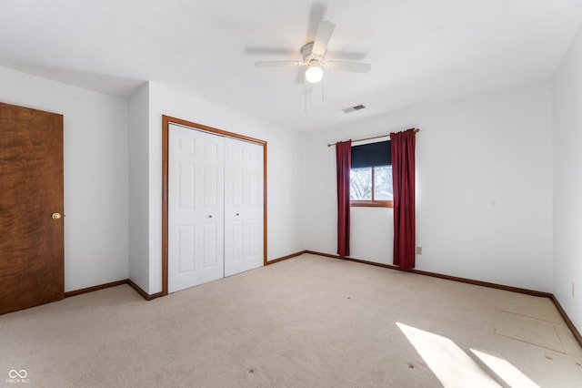 unfurnished bedroom with ceiling fan, a closet, and light carpet