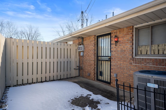 snow covered property entrance featuring cooling unit