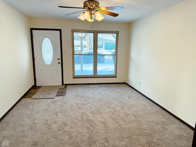 entrance foyer featuring a textured ceiling, carpet floors, and ceiling fan