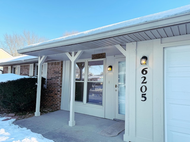 snow covered property entrance with covered porch