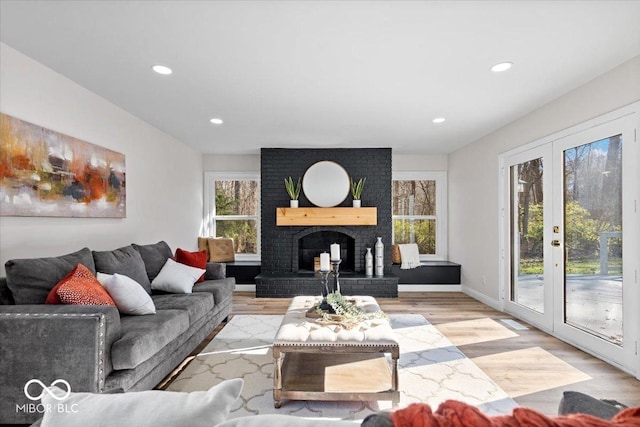 living room featuring a fireplace, light wood-type flooring, and french doors