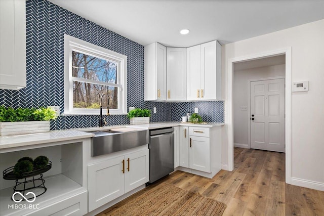 kitchen featuring stainless steel dishwasher, light hardwood / wood-style flooring, backsplash, white cabinets, and sink