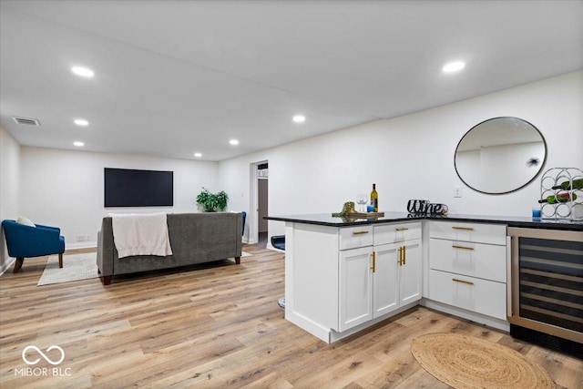 kitchen with kitchen peninsula, white cabinetry, wine cooler, and light hardwood / wood-style flooring