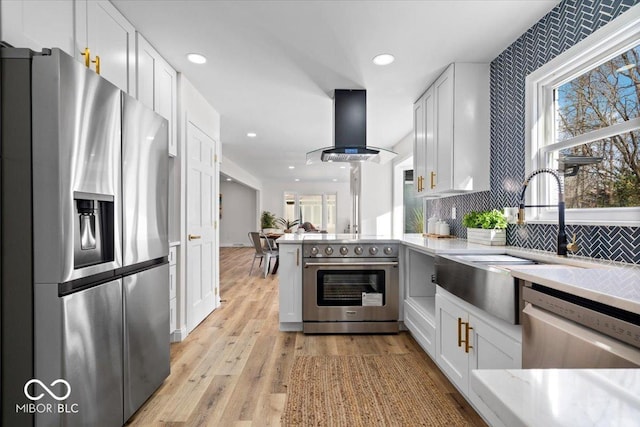 kitchen featuring extractor fan, light hardwood / wood-style flooring, stainless steel appliances, white cabinets, and sink