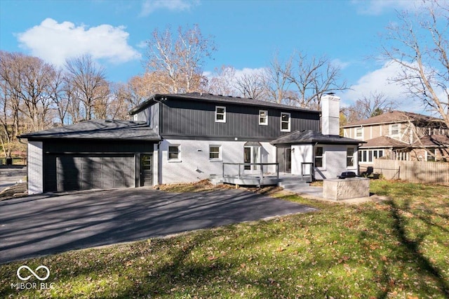 rear view of property with a garage, a wooden deck, and a yard