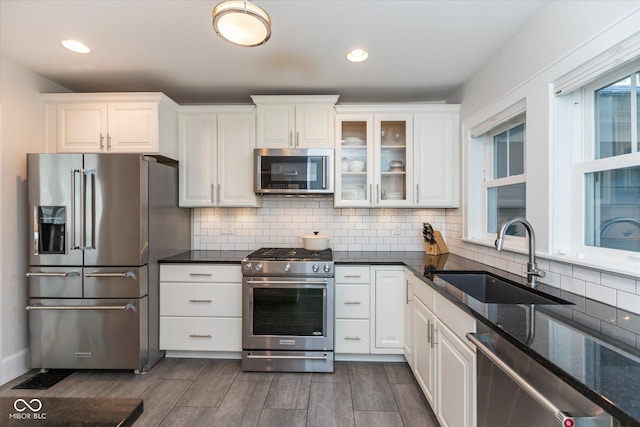 kitchen with sink, white cabinetry, tasteful backsplash, dark stone counters, and appliances with stainless steel finishes