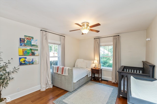 bedroom with ceiling fan, dark hardwood / wood-style flooring, and multiple windows