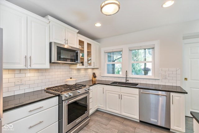 kitchen featuring stainless steel appliances, white cabinets, decorative backsplash, and sink