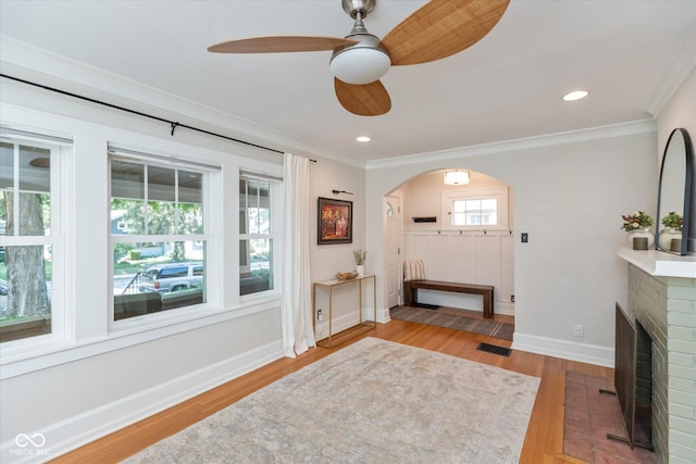 interior space featuring ornamental molding, ceiling fan, a fireplace, and hardwood / wood-style flooring