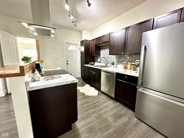 kitchen featuring stainless steel appliances, a kitchen island, backsplash, dark brown cabinets, and sink