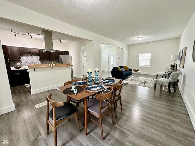 dining room with a textured ceiling and dark hardwood / wood-style floors