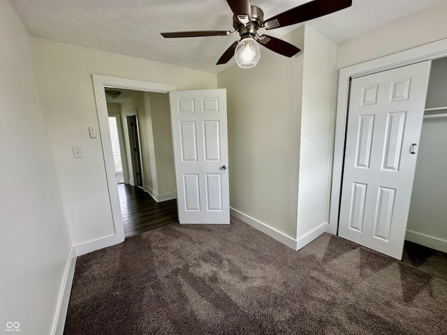 unfurnished bedroom with ceiling fan, a closet, and dark carpet