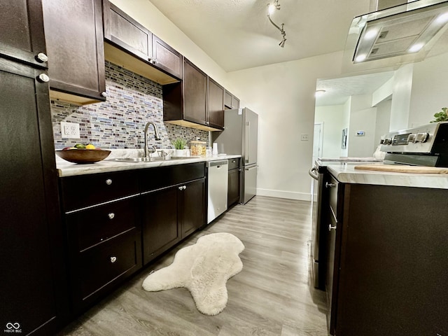 kitchen with appliances with stainless steel finishes, light wood-type flooring, decorative backsplash, sink, and dark brown cabinets