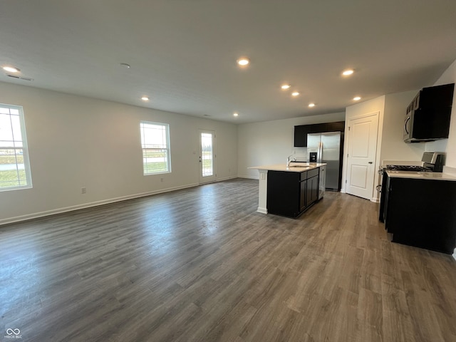 kitchen featuring stainless steel appliances, dark hardwood / wood-style flooring, sink, and an island with sink