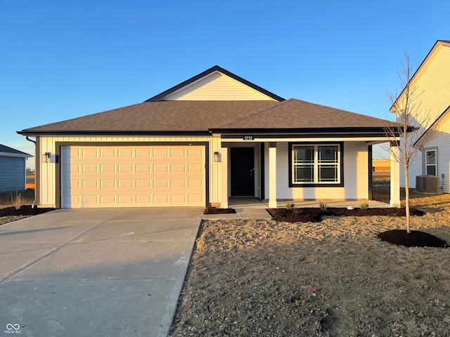 single story home with covered porch, cooling unit, and a garage