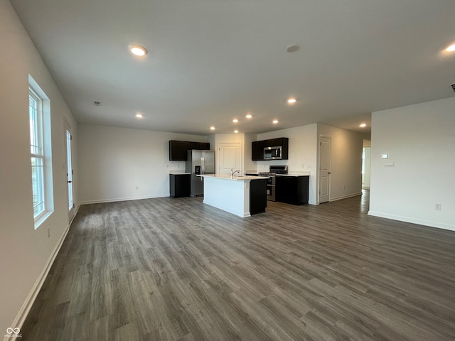 kitchen featuring appliances with stainless steel finishes, dark wood-type flooring, a kitchen island with sink, and sink