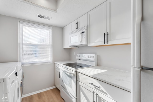 kitchen with white appliances, a textured ceiling, washing machine and dryer, light wood-type flooring, and white cabinets