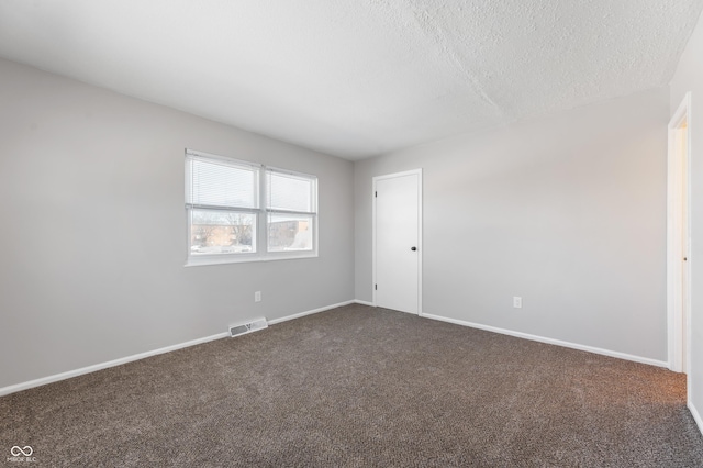 empty room featuring a textured ceiling and dark carpet