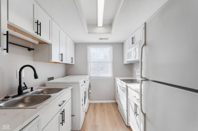 clothes washing area with sink, independent washer and dryer, and light hardwood / wood-style flooring