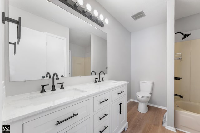 full bathroom with toilet, wood-type flooring, vanity, and tub / shower combination