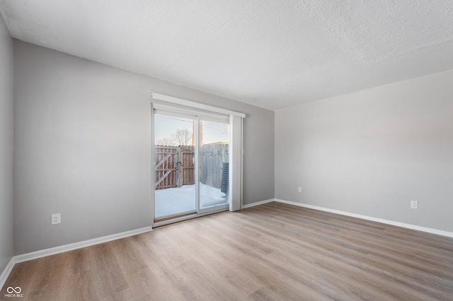 spare room featuring a textured ceiling and light hardwood / wood-style floors