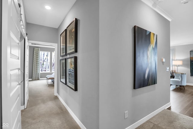 hallway with light colored carpet and a barn door