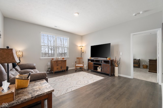 living room featuring dark wood-type flooring and a textured ceiling