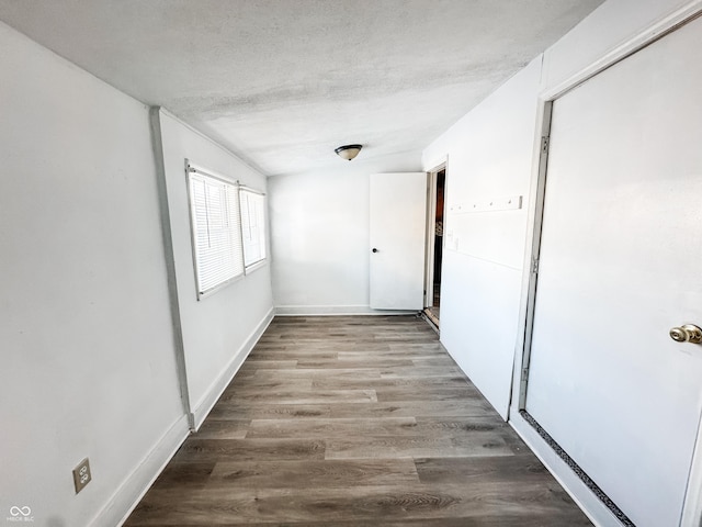 hallway with light wood-type flooring and a textured ceiling