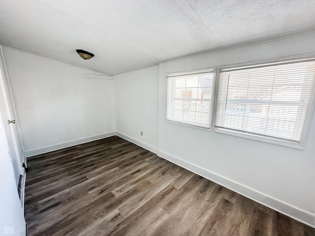 unfurnished room featuring lofted ceiling, dark wood-type flooring, and a textured ceiling