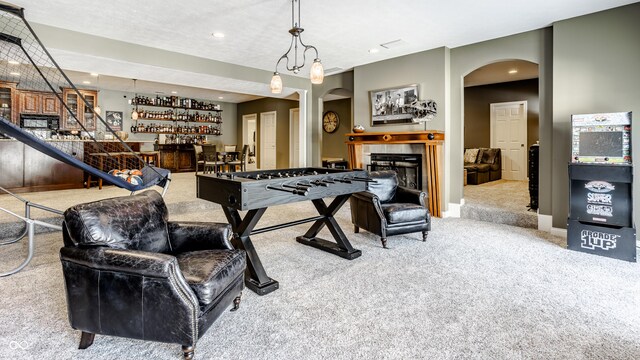 8526 Oakmont Ln, Indianapolis, IN 46260 - game room with indoor bar, a tiled fireplace, and light colored carpet