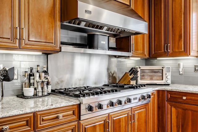 8526 Oakmont Ln, Indianapolis, IN 46260 - kitchen featuring light stone countertops, stainless steel gas cooktop, decorative backsplash, and exhaust hood