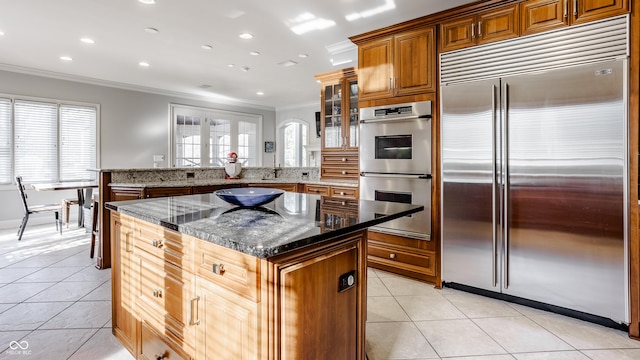 8526 Oakmont Ln, Indianapolis, IN 46260 - kitchen with light tile patterned floors, dark stone countertops, ornamental molding, appliances with stainless steel finishes, and a kitchen island