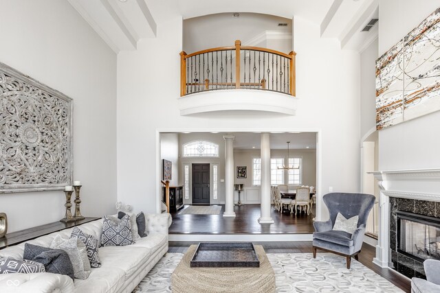 8526 Oakmont Ln, Indianapolis, IN 46260 - living room featuring decorative columns, a towering ceiling, a high end fireplace, beam ceiling, and hardwood / wood-style floors