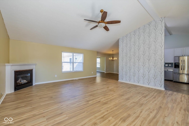 unfurnished living room featuring high vaulted ceiling, ceiling fan with notable chandelier, and light hardwood / wood-style floors