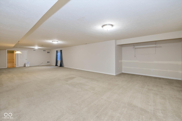 basement featuring light carpet and a textured ceiling