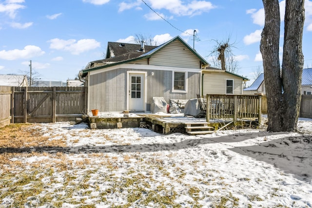 snow covered back of property featuring a deck