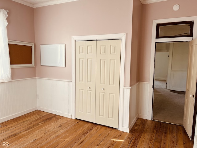 unfurnished bedroom with crown molding, wood-type flooring, and a closet