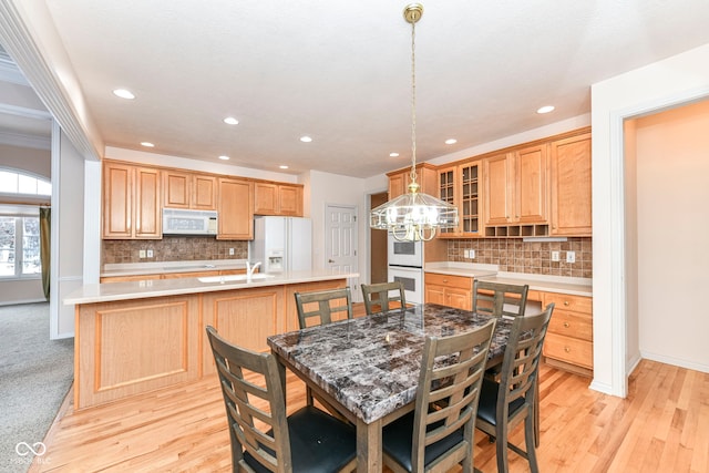 kitchen with decorative backsplash, decorative light fixtures, white appliances, and light hardwood / wood-style flooring